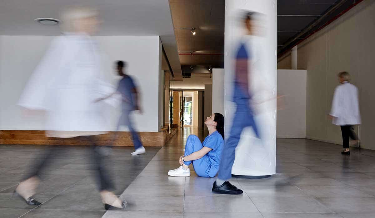 Shot of a young female doctor looking tired while working in a busy hospital